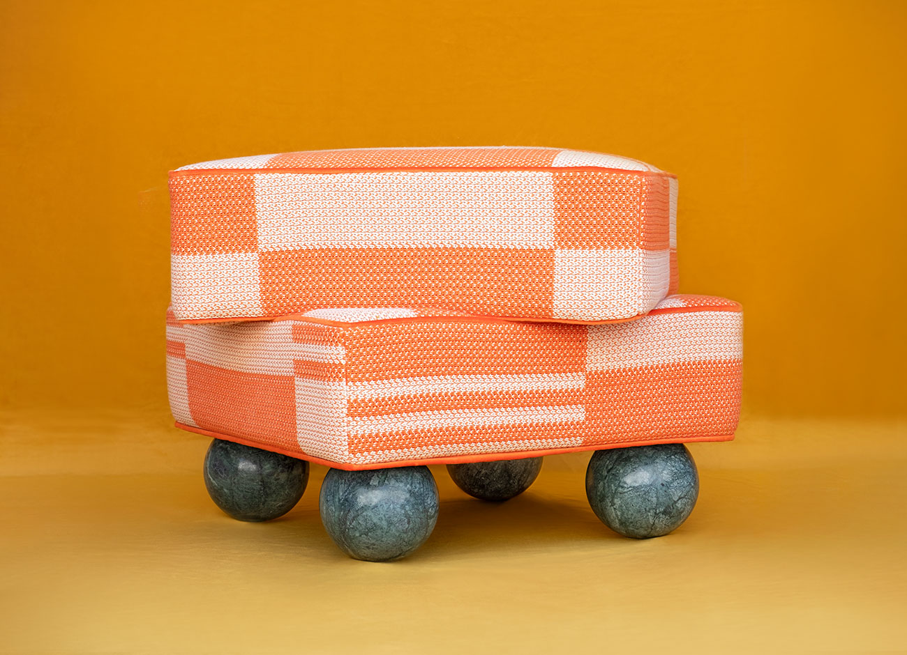 Madonna stool Madonna stool upholstered in kirkby checkerboard knit tangelo (k5299/01) squared decorative knit orange fabric, paired with verde guatemala marble sphere legs, set against an orange background.
