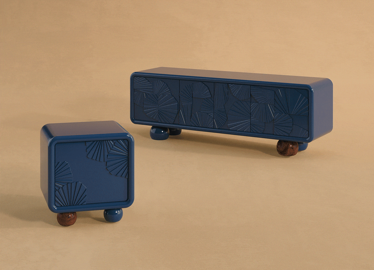 A minimalist studio shot of the mon ooh sideboard and mon ooh bedside table by malabar. Both pieces feature a high-gloss deep blue lacquered finish with rounded edges and intricate, hand-carved textured "ginkgo" fan patterns on the door fronts. The furniture is supported by playful, oversized spherical feet in a mix of matching blue lacquer and polished dark walnut wood, set against a warm beige background.