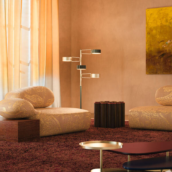 Viv Id chaise longue in a warm-toned living room interior, featuring Tiger Silk 002 fabric by Dedar with yellow highlights and a Travertino Rosso structure. The space also includes the La Toile center table, Kensington Tic-Tac-Toe table, and Brompton Floor Lamp.