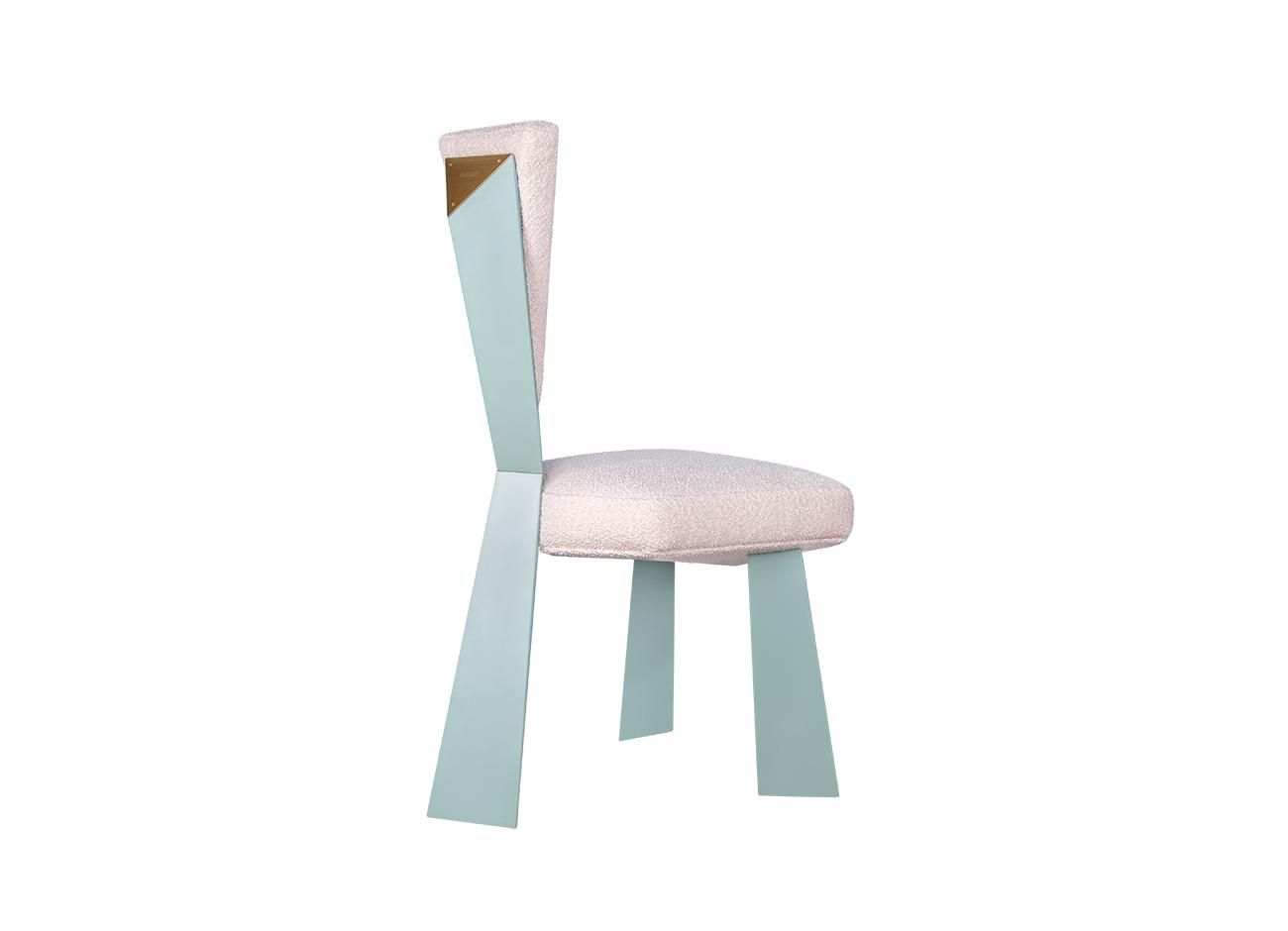 Kju bist dining chair by malabar photographed at a 45-degree back angle against a white background, emphasizing its cubist-inspired angular geometry, planar silhouette, blue lacquered legs, and bouclé fabric upholstery.