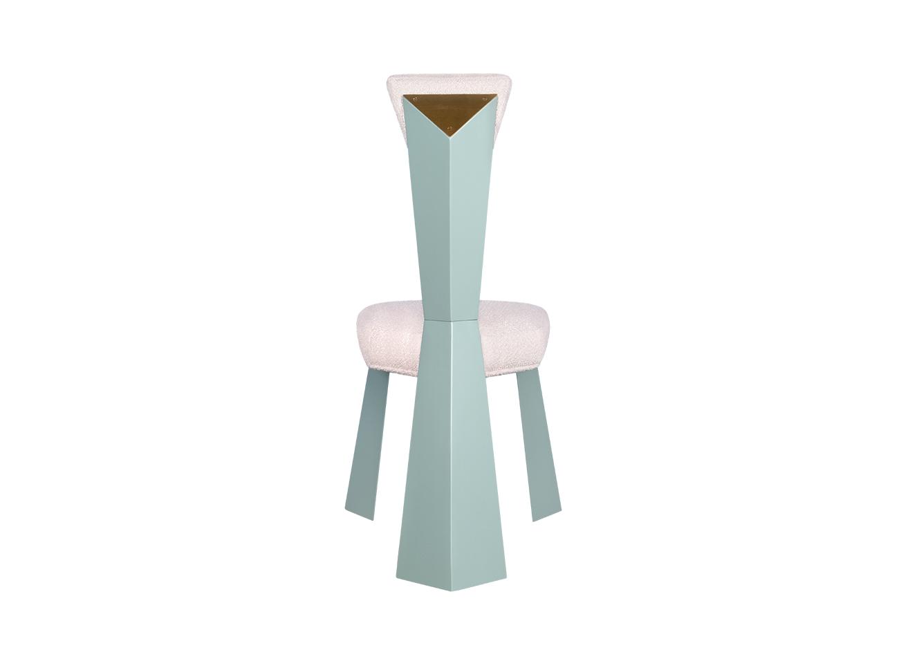 Kju bist dining chair by malabar photographed from the back against a white background, revealing its sculptural cubist-inspired geometry, angular backrest, blue lacquered legs, and bouclé fabric upholstery.