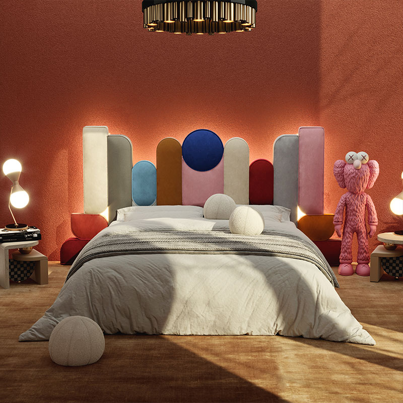 Ej ee bed with red, pink, yellow, gray and white fabrics in a cozy bedroom.