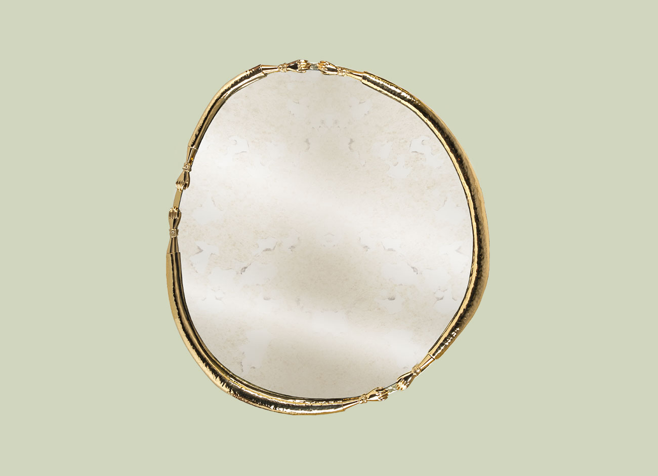 La Joie Mirror Oval La Joie Mirror designed for vertical wall mounting, featuring a play of reflections and light. Handmade with hammered gold and antique bronze mirror finishes, set against a green background.