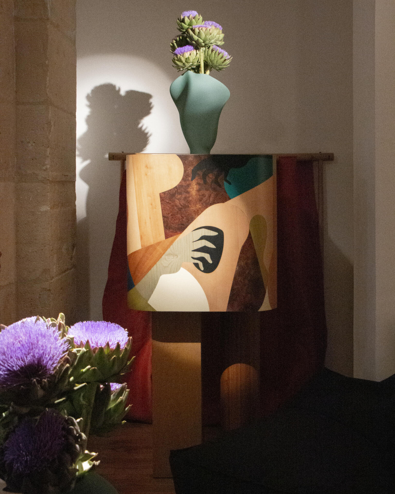 Ih maj in cabinet at paris design week, highlighted with dramatic lighting and topped with a vase.