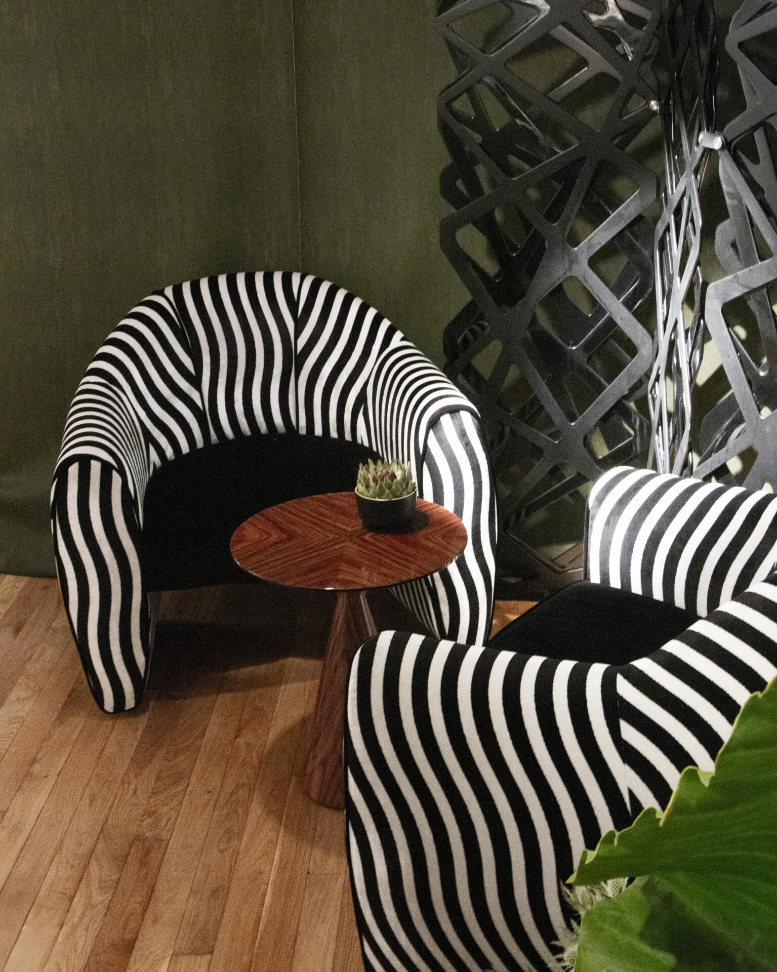 Two viginti xx armchairs upholstered in wavy striped fabric next to a wooden side table.