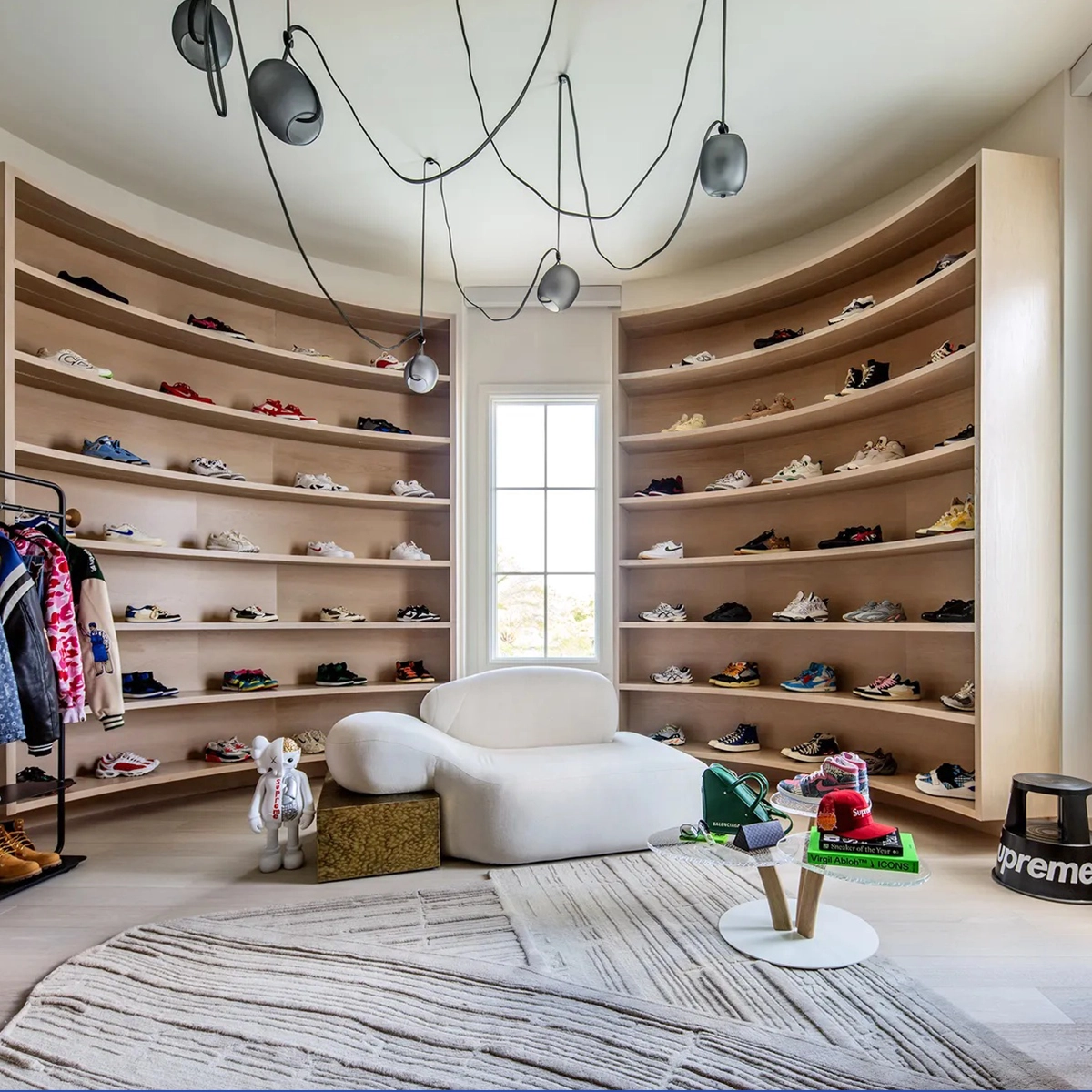 Viv id chaise longue in a dressing space, next to circular shelves filled with shoes and sneakers arranged around the piece, with a window in the background. Space designed by shanna gatanis.