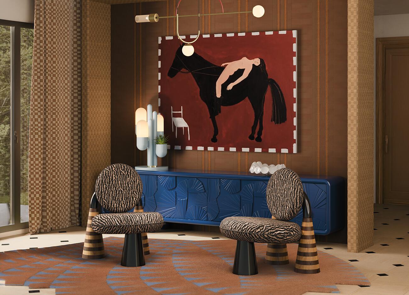 A luxurious, eclectic living room featuring two totora armchairs by malabar in the foreground. The armchairs have circular backs and seats upholstered in a zebra-patterned fabric, supported by sculptural, cone-shaped wooden legs with tiered rings. In the background, a vibrant sapphire blue mon ooh sideboard features intricate geometric carvings. On top of it sits the light blue cactus table lamp by creativemary. The back wall is covered in textured brown wallpaper, centered by a large expressionist painting of a black horse with a reclining figure on its back against a deep red background. The room is illuminated by a tortona suspension lamp with brass arms and a red arch. The floor is light wood with black diamond accents, partially covered by a jagged-edge rug in terracotta and blue geometric patterns.