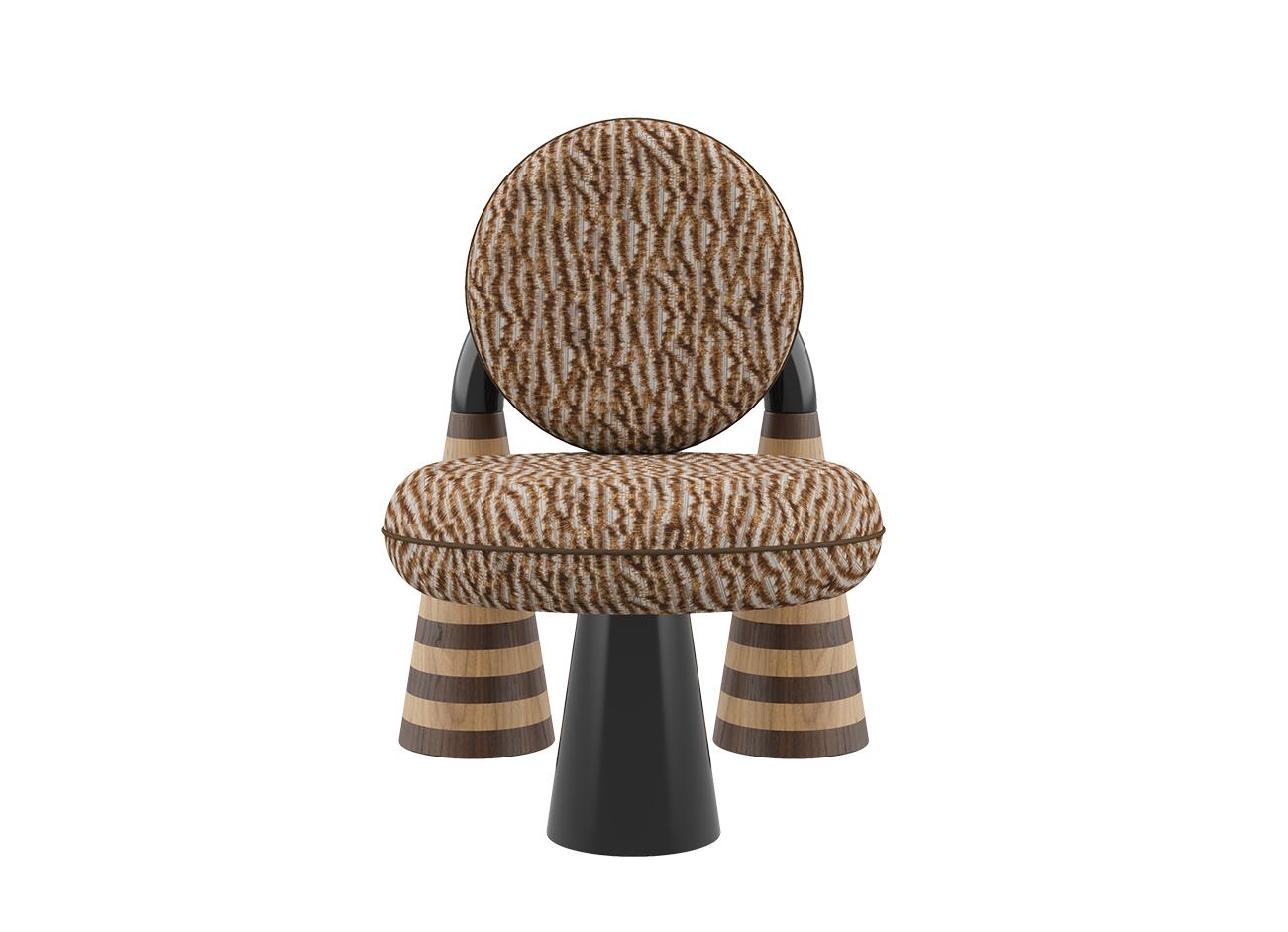 A front-facing studio shot of the totara armchair by malabar. The armchair features circular, plush cushions upholstered in a textured brown and ochre misia fabric with an organic, tiger-stripe pattern. The sculptural design is anchored by a high-gloss black lacquer arch and a central black conical front leg, contrasted by two rear conical legs featuring horizontal oak and smoked walnut marquetry stripes.