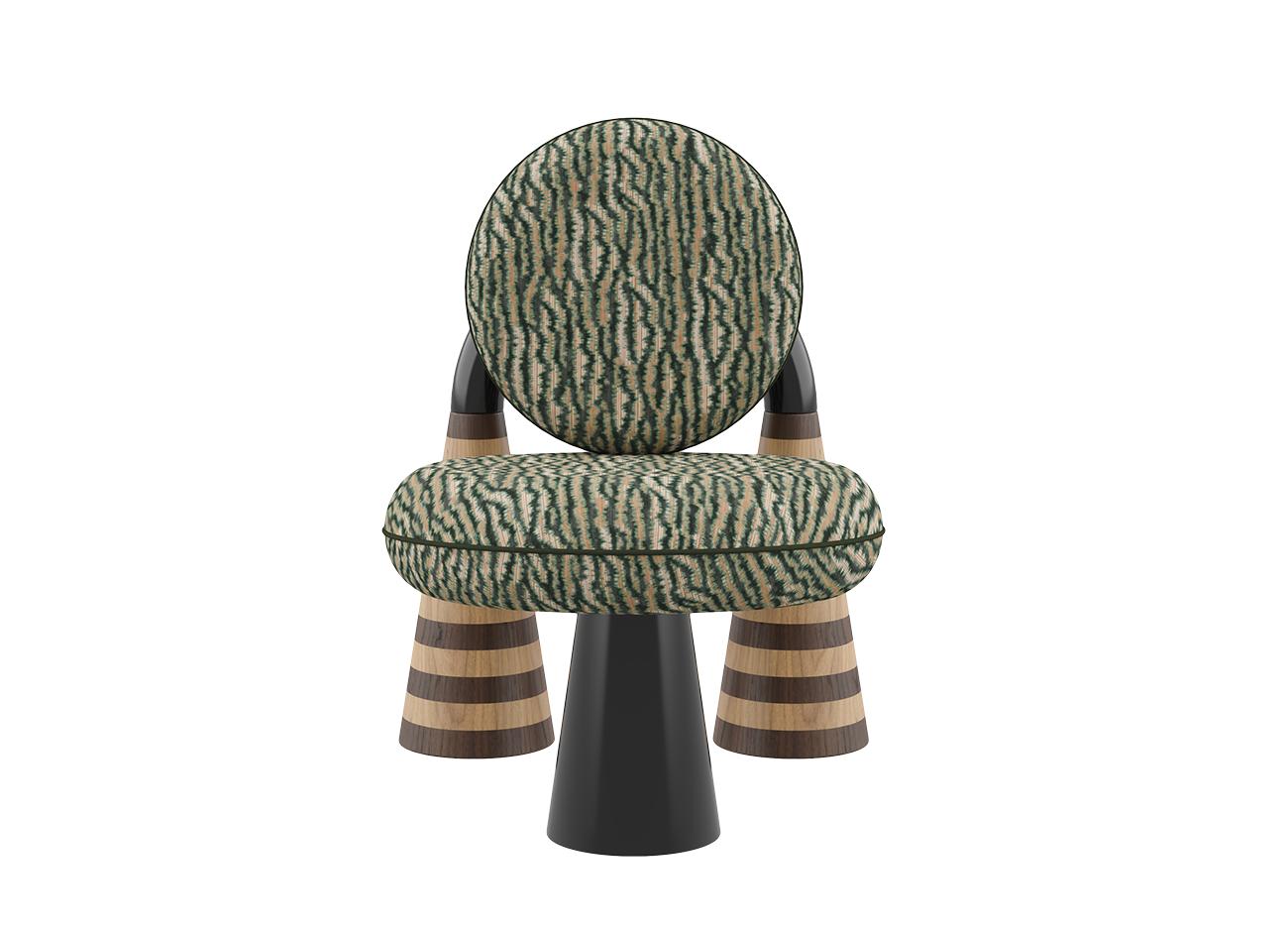 A front-facing studio shot of the totara armchair by malabar. This version is upholstered in a forest green and beige misia fabric with a rhythmic, textured pattern. The armchair's avant-garde silhouette is highlighted by its architectural black lacquer arch and distinctive striped wood marquetry legs, blending natural materials with bold, modern geometry.