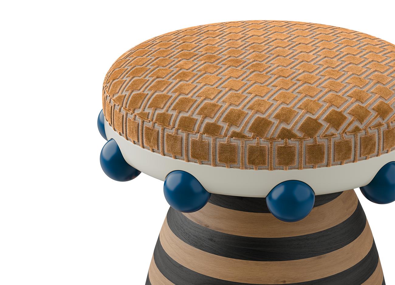A close-up detail of the krom mea stool focusing on the tactile precision of the orange velvet pattern. The image captures the smooth finish of the blue decorative spheres and the textured edge of the upholstered seat.